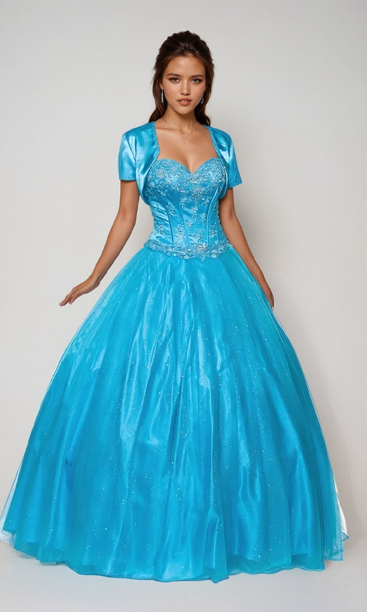 A woman stands against a plain light background wearing the Juliet 332 Long Prom Dress—a bright blue sweetheart ball gown featuring a fitted beaded bodice and a short matching bolero jacket.